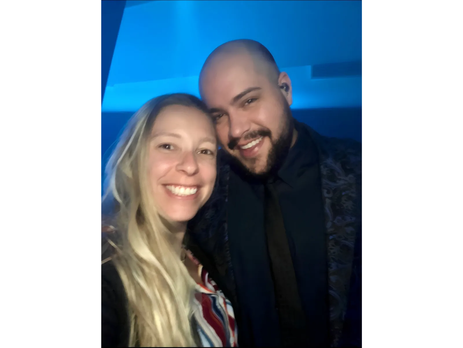 Pilar Moretzsohn e outro participante sorriem em uma selfie sob luz azul.