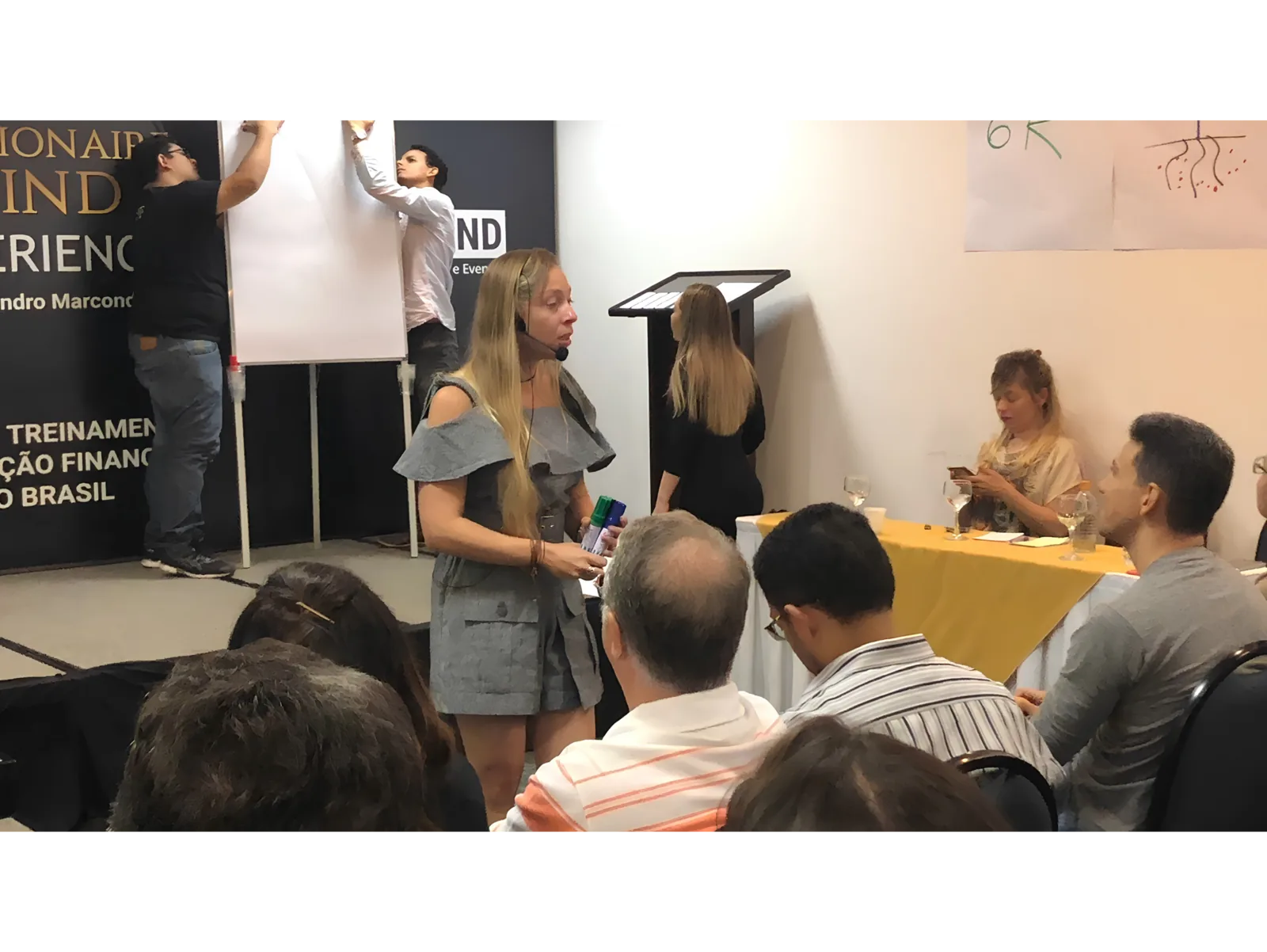 Pilar Moretzsohn conversa com participantes em uma sala de evento.
