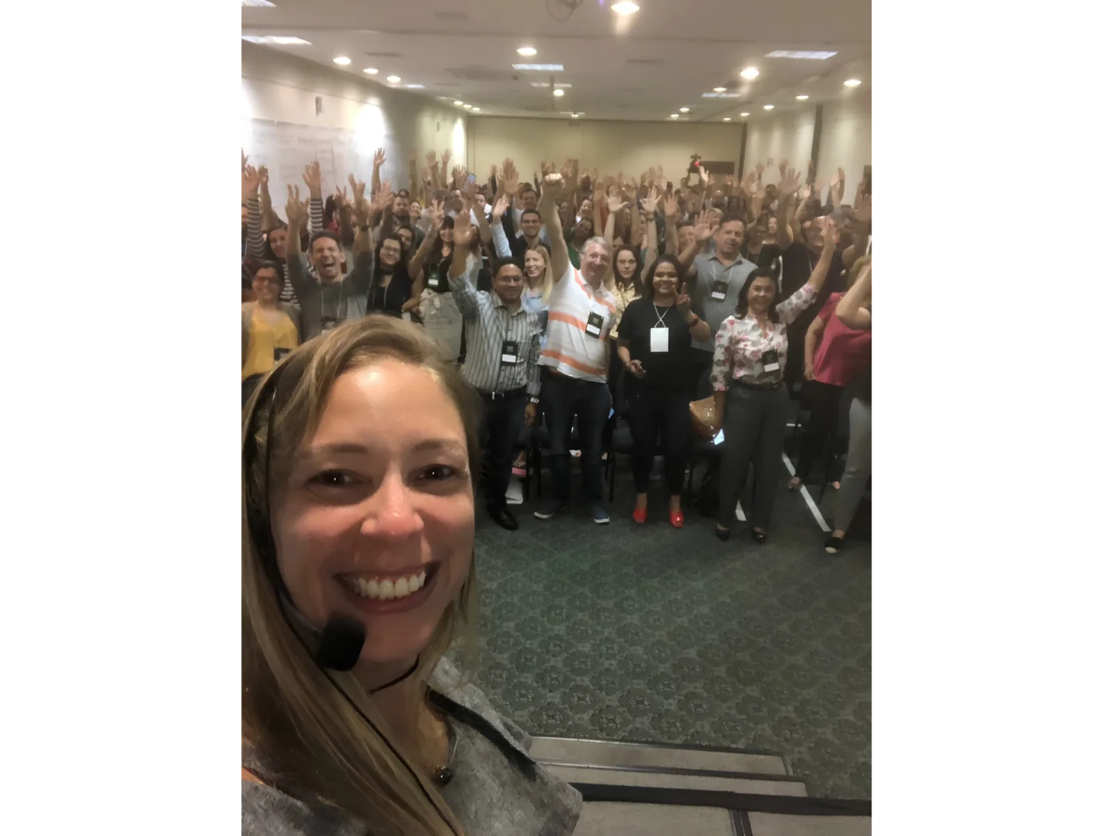 Pilar Moretzsohn faz uma selfie com uma plateia de braços levantados.