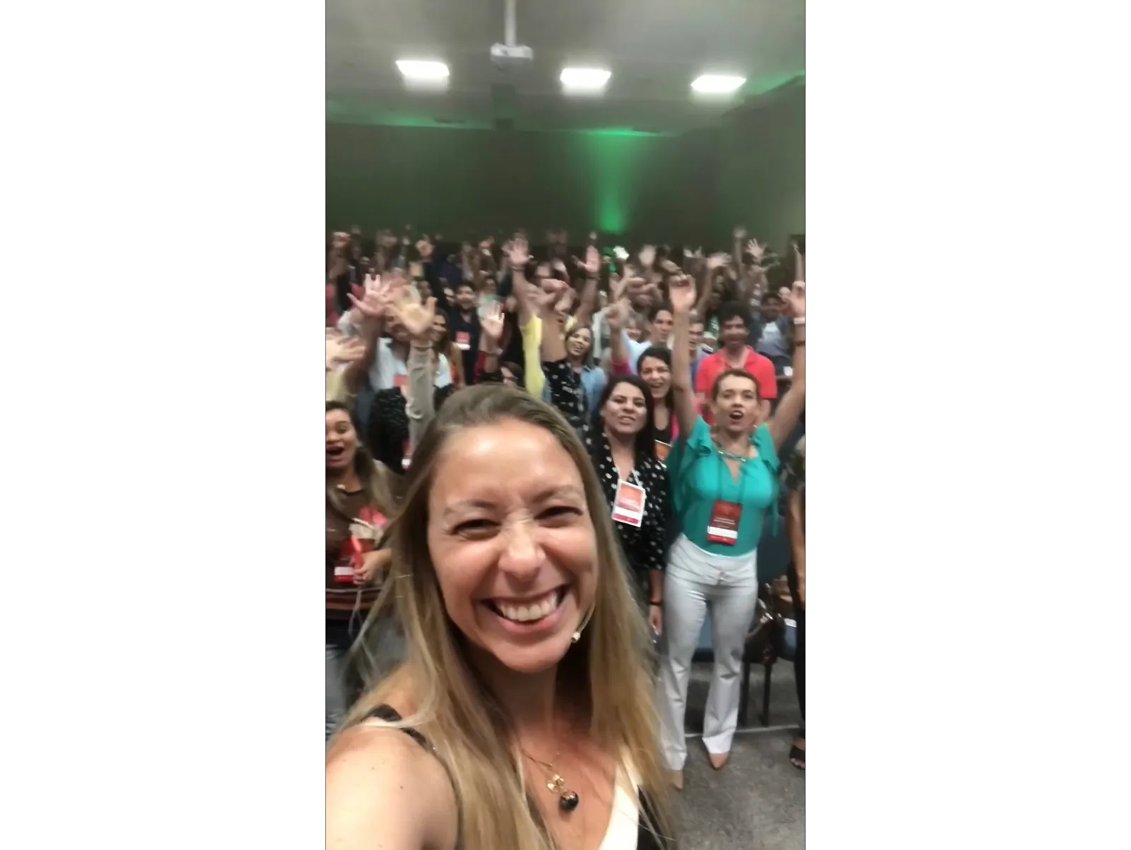 Pilar Moretzsohn sorri em primeiro plano diante de uma plateia.