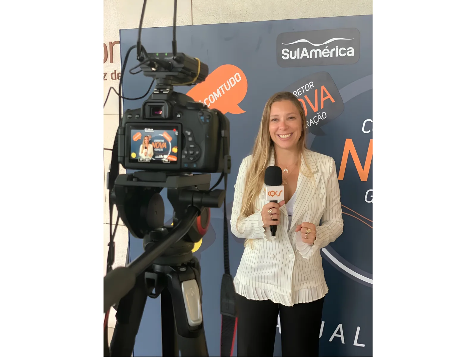 Pilar Moretzsohn segura um microfone diante de uma câmera em um evento.