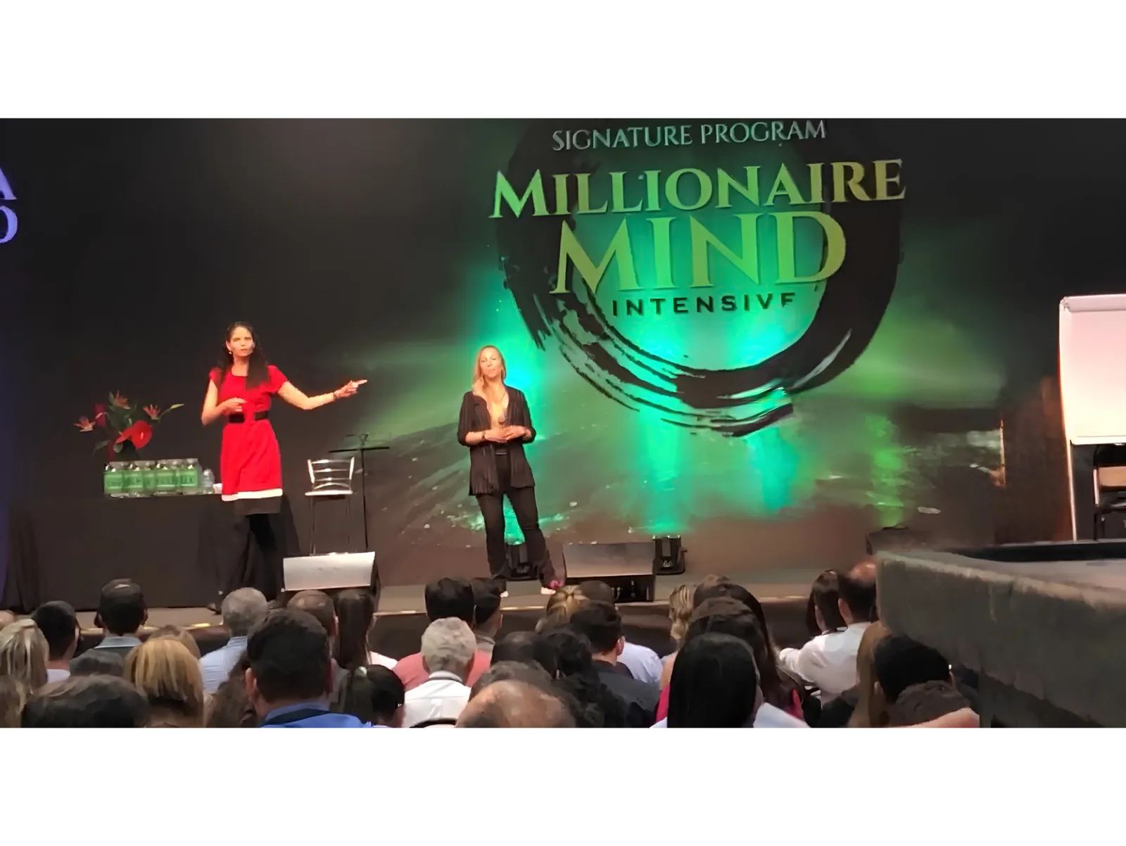 Pilar Moretzsohn e outra profissional estão no palco diante de uma plateia.
