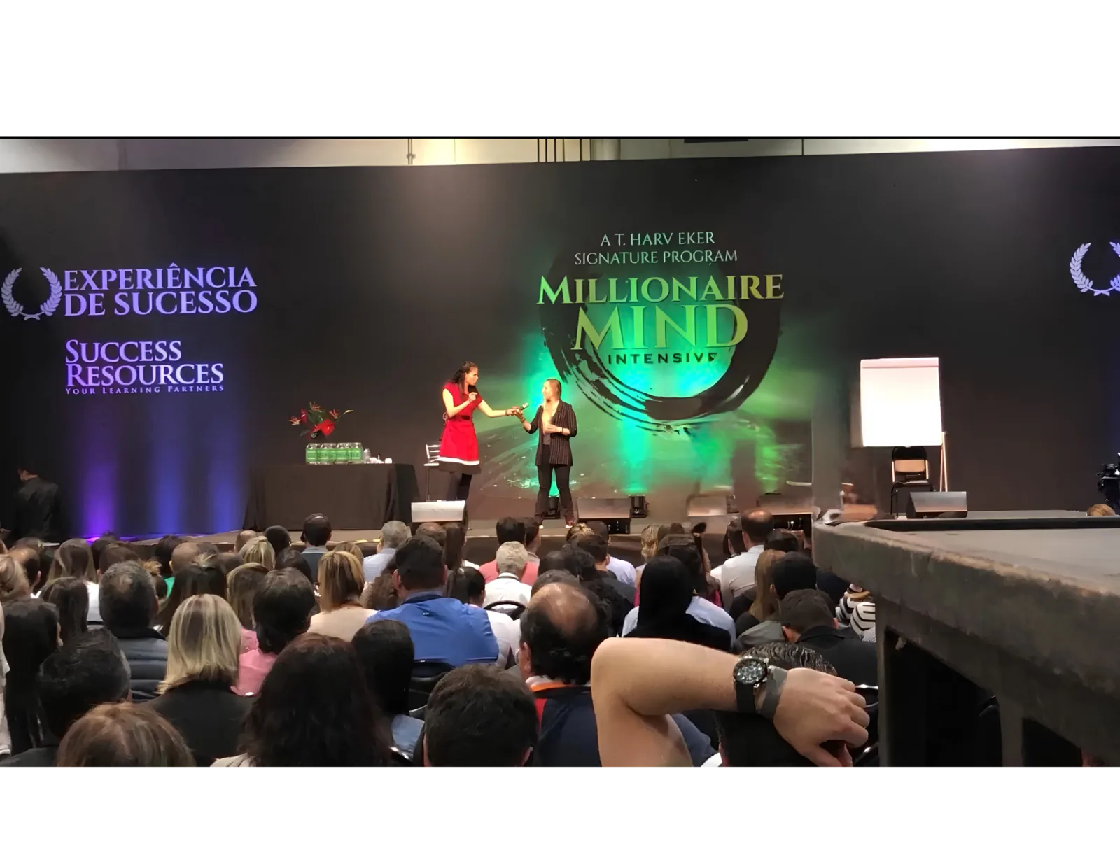 Uma profissional oferece um microfone a Pilar Moretzsohn no palco.