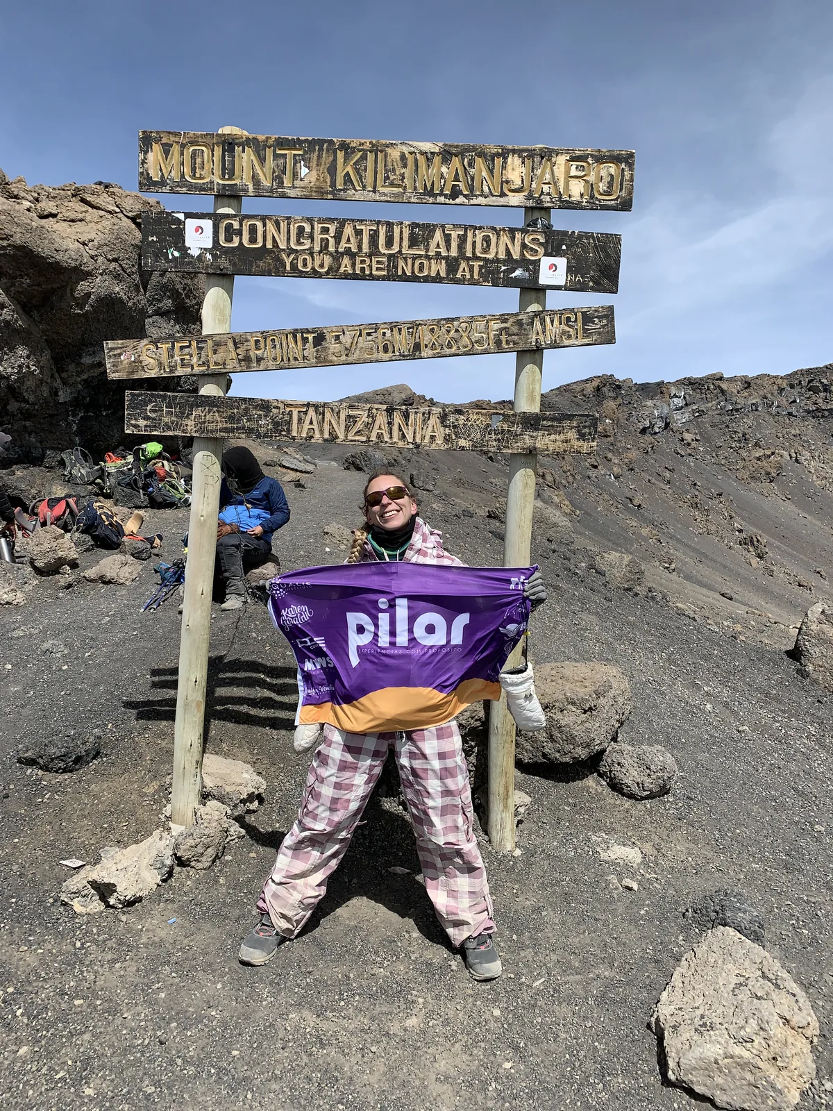 Pilar Moretzsohn segura uma bandeira diante da placa de Stella Point, no Kilimanjaro.