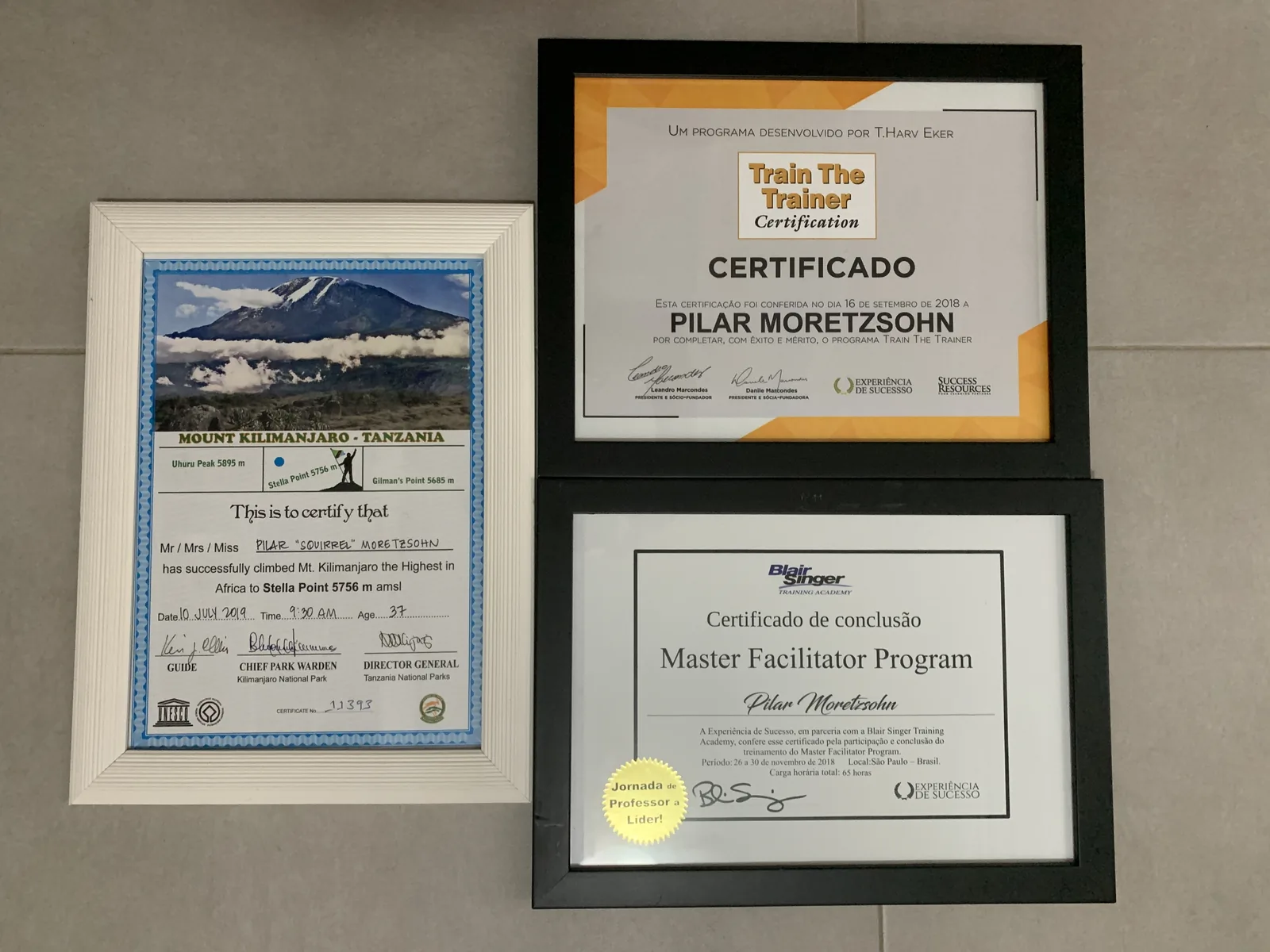 Certificados de Pilar Moretzsohn no Train the Trainer Certification e no Master Facilitator Program, ao lado do certificado de chegada a Stella Point, no Kilimanjaro.
